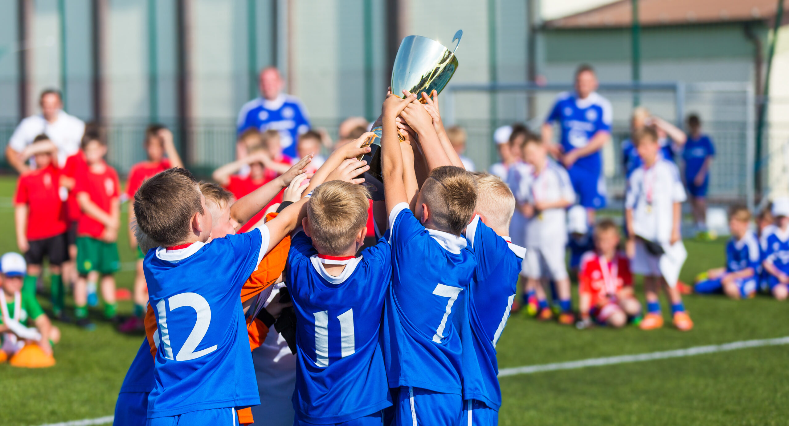 Young Soccer Players Holding Trophy. Boys Celebrating Soccer Football Championship. Winning team of sport tournament for kids children.)